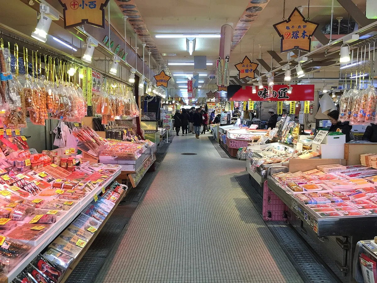 Covered aisle of the Hakodate Morning Market lined with stalls selling dried seafood and boxed crab and roe