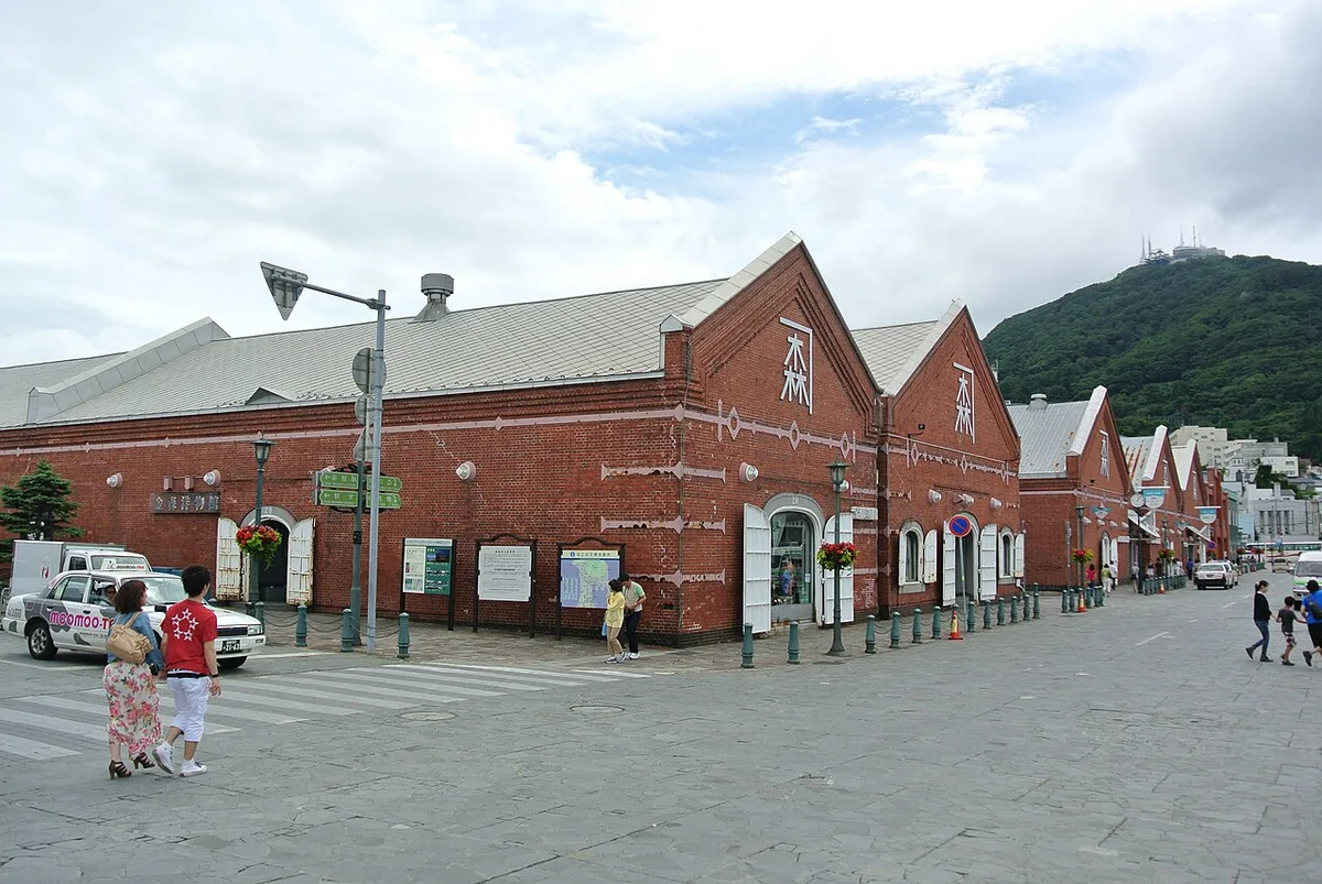 The Kanemori Red Brick Warehouses on a stone-paved street in Hakodate's Bay Area, with Mt. Hakodate behind
