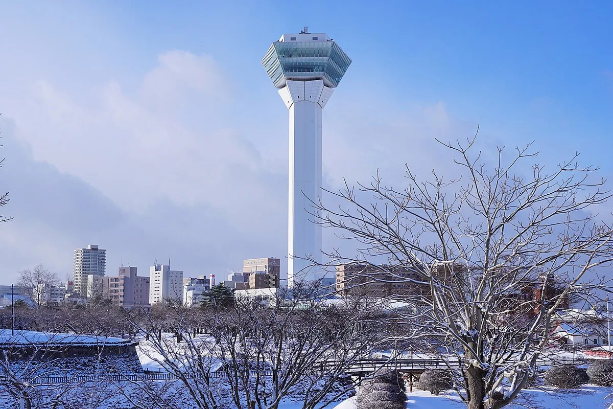 White Goryokaku Tower rising above bare, snow-dusted trees in Hakodate