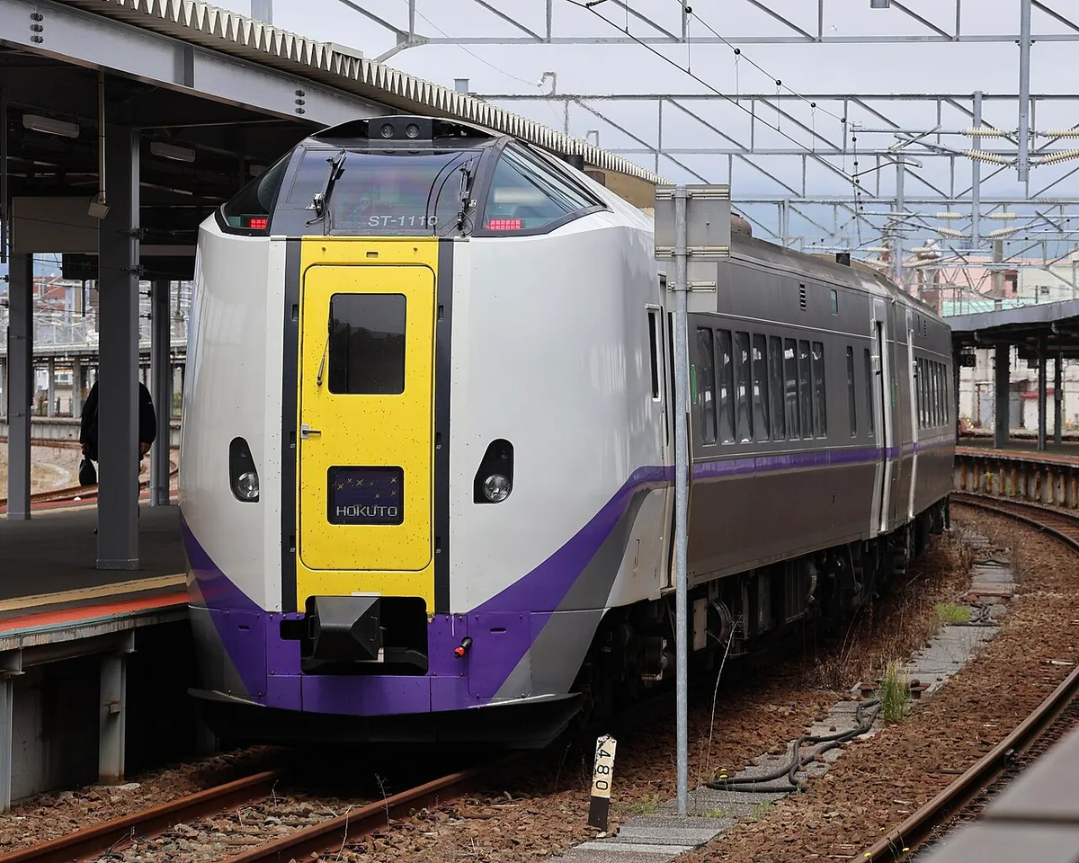Front of a white, yellow and purple Hokuto train at a platform in Hakodate Station