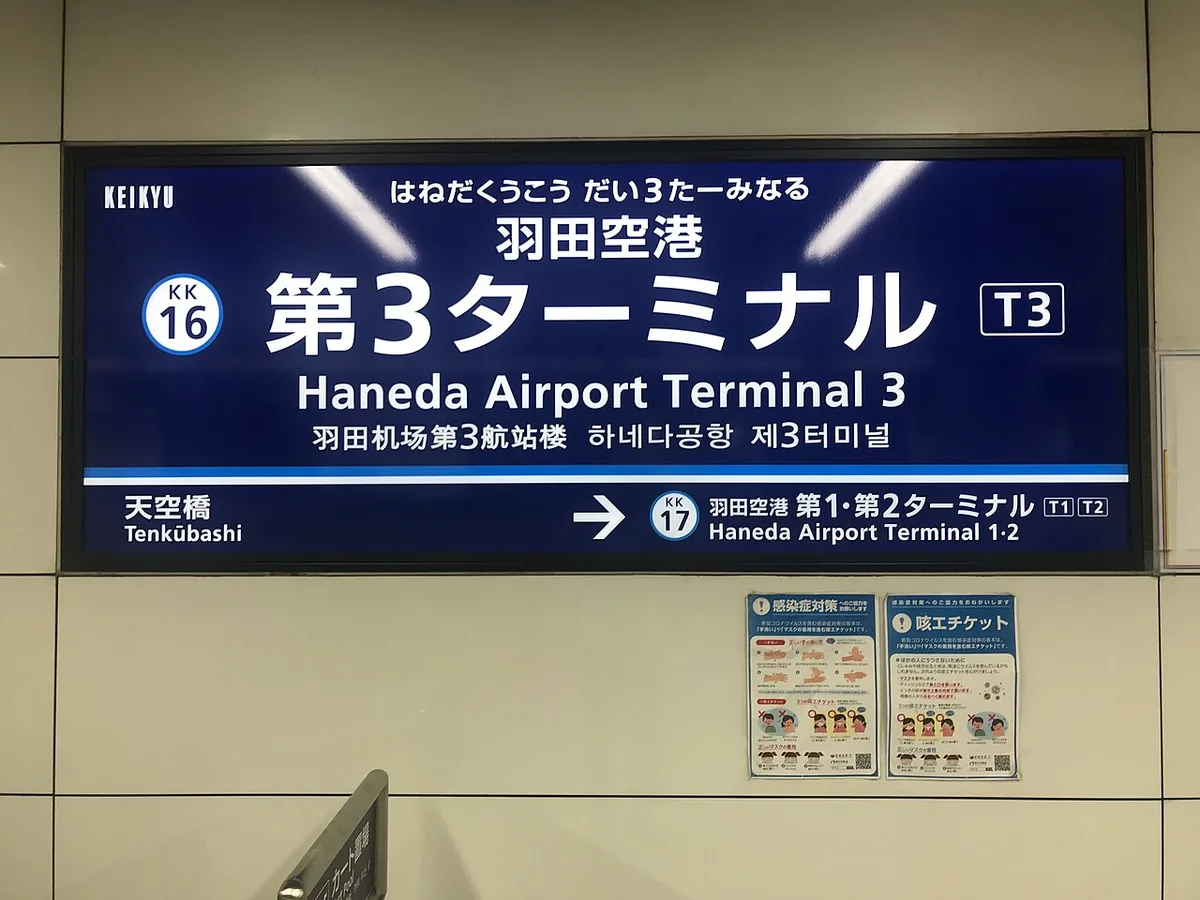 Blue Keikyu station name sign on a tiled wall reading Haneda Airport Terminal 3 (KK16) in Japanese and English, with an arrow to Haneda Airport Terminal 1·2