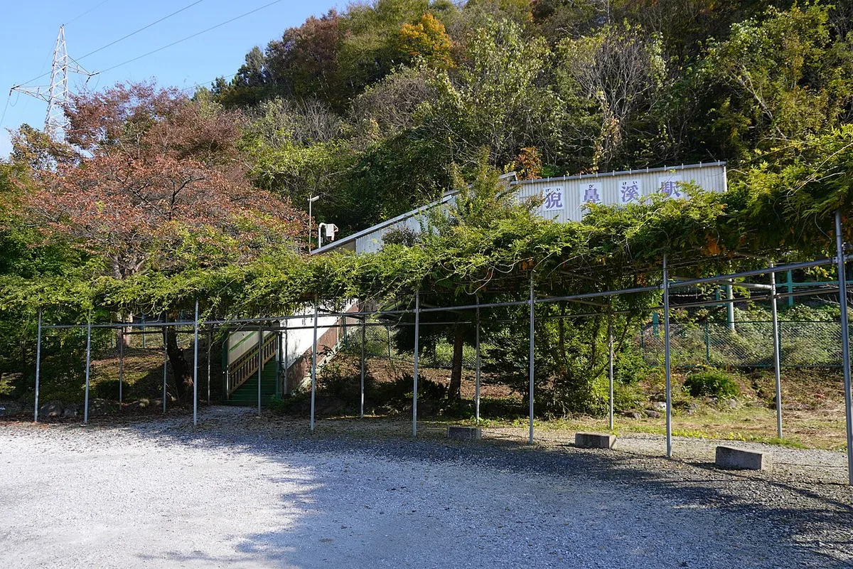 Small Geibikei Station building behind a trellis and gravel forecourt, with autumn trees on the hill