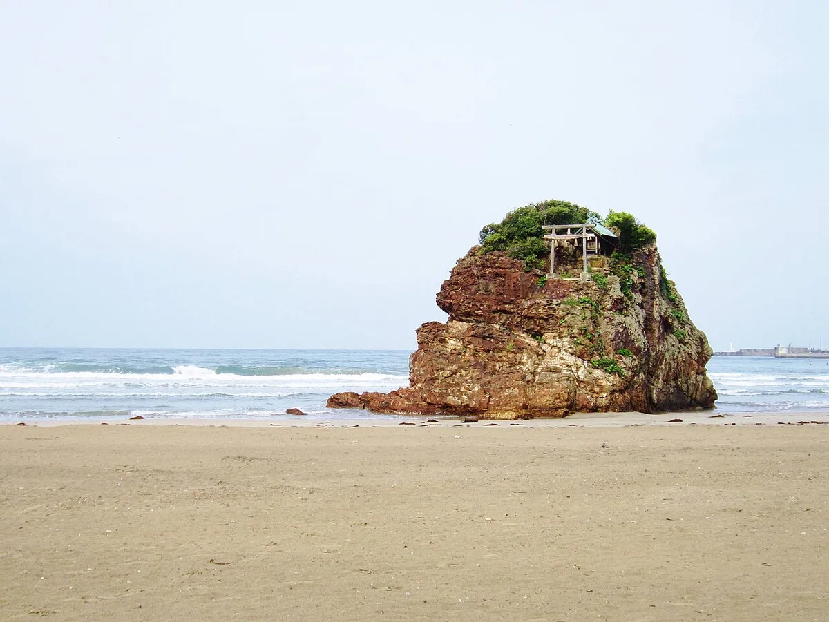 Bentenjima, a rock with a small shrine on top, standing on the sand of Inasa Beach
