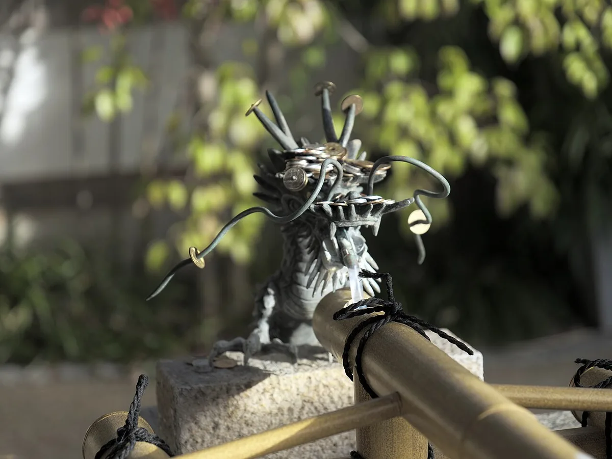 Bronze dragon spout feeding water over bamboo at a shrine temizuya purification fountain in Kyoto