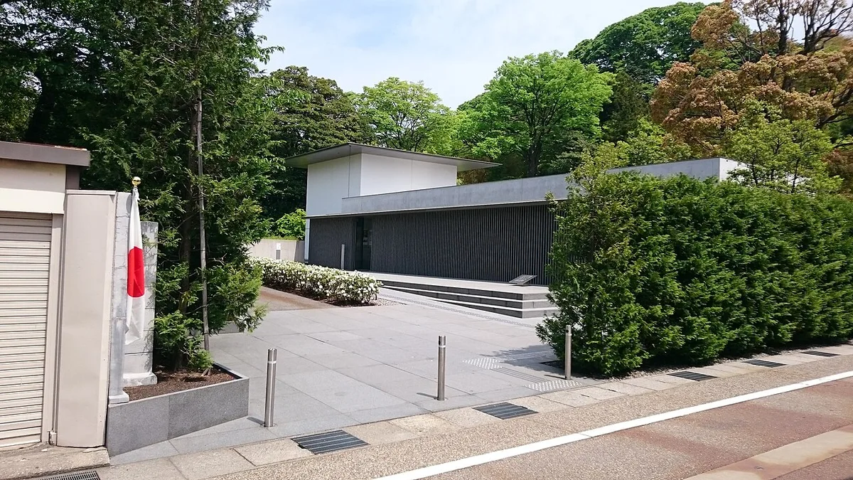 Low modern concrete building of the D. T. Suzuki Museum among trees, seen from the street