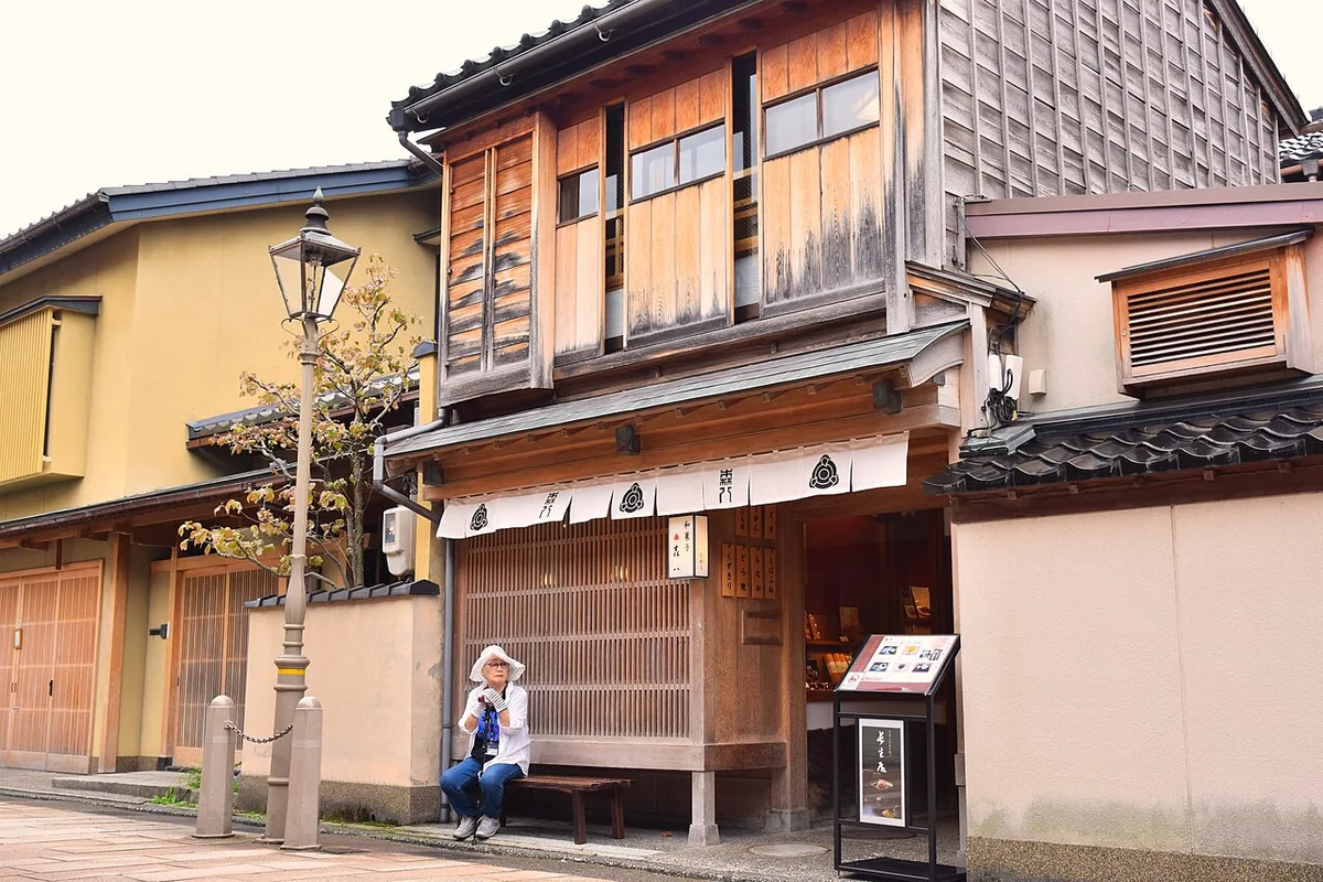 Two-storey wooden teahouse with fine lattice front and white noren on the stone-paved street of Higashi Chaya, Kanazawa