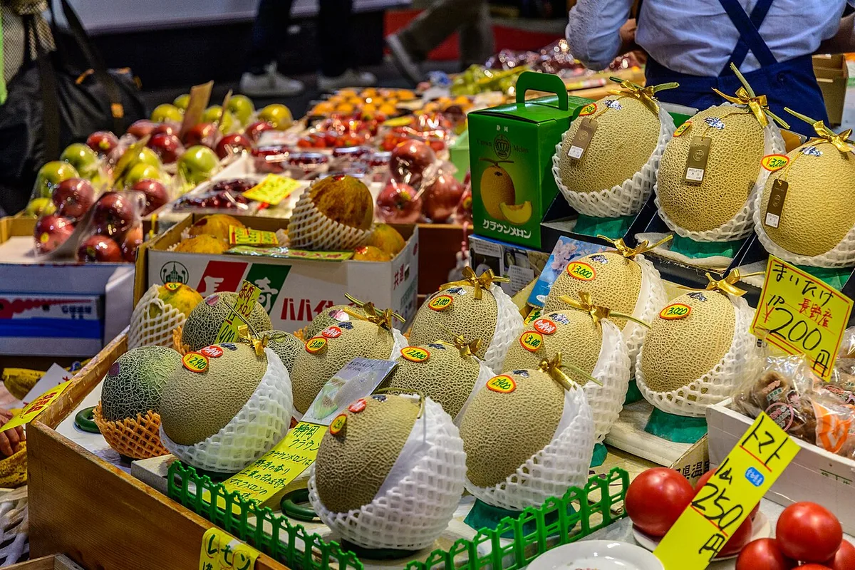 Fruit stall at Omicho Market, Kanazawa, with netted melons in gift boxes, apples and tomatoes under handwritten price cards