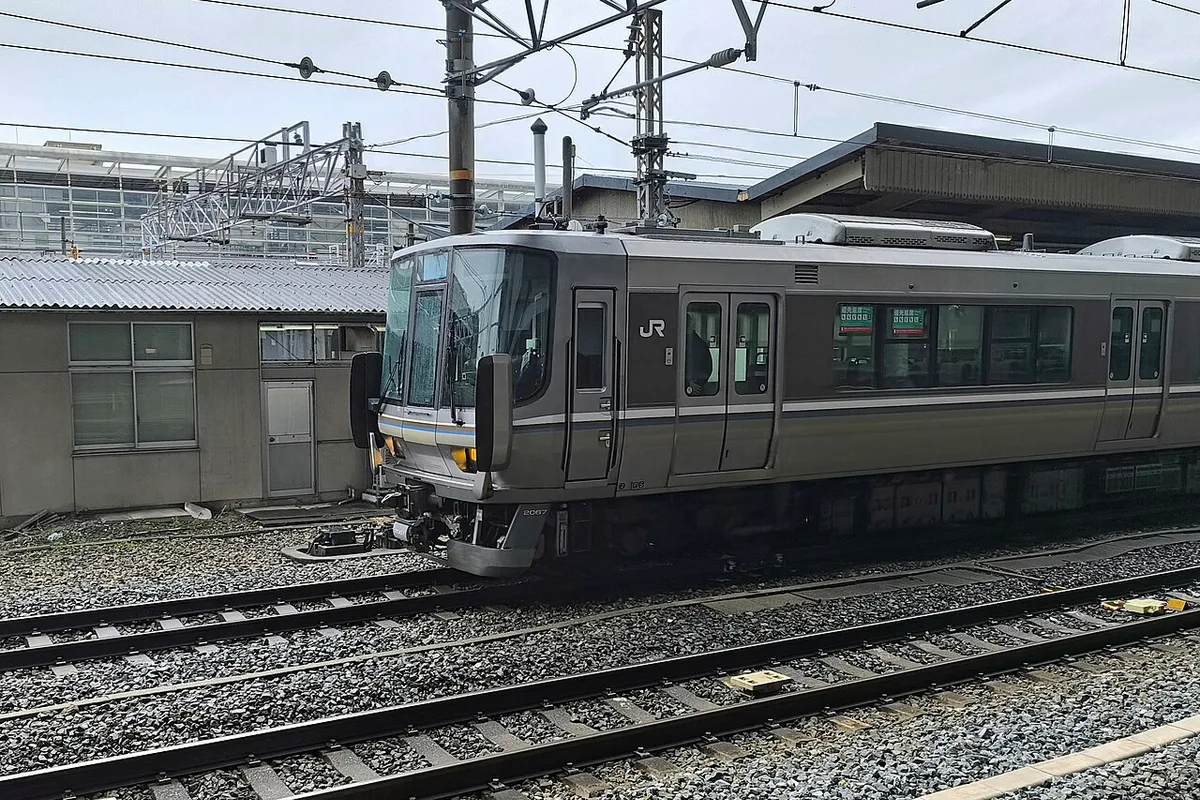 Silver JR West 223 series Special Rapid train with a brown stripe standing at a platform of Kyoto Station