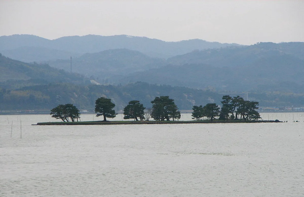 Yomegashima, a small pine-covered islet in Lake Shinji, with hills behind the lake near Matsue