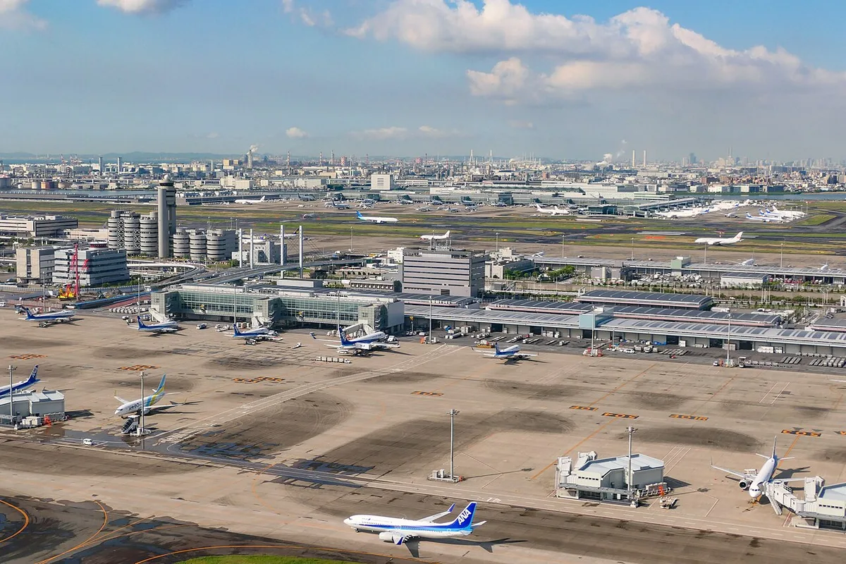 Aerial view of Haneda Airport terminals and aprons with parked aircraft and the control tower