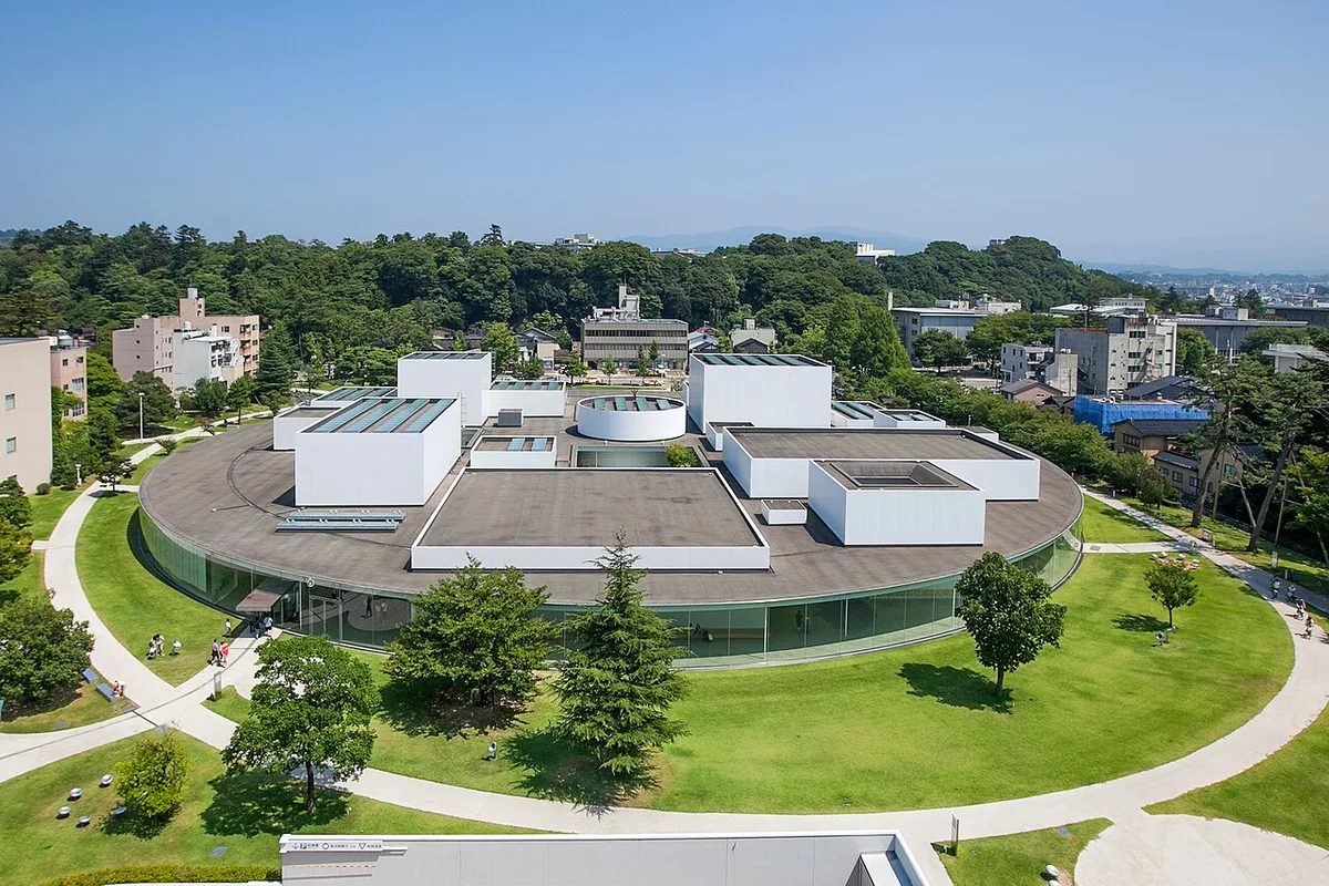 The round glass-walled 21st Century Museum of Contemporary Art seen from above, with white box galleries on its roof and lawns around it