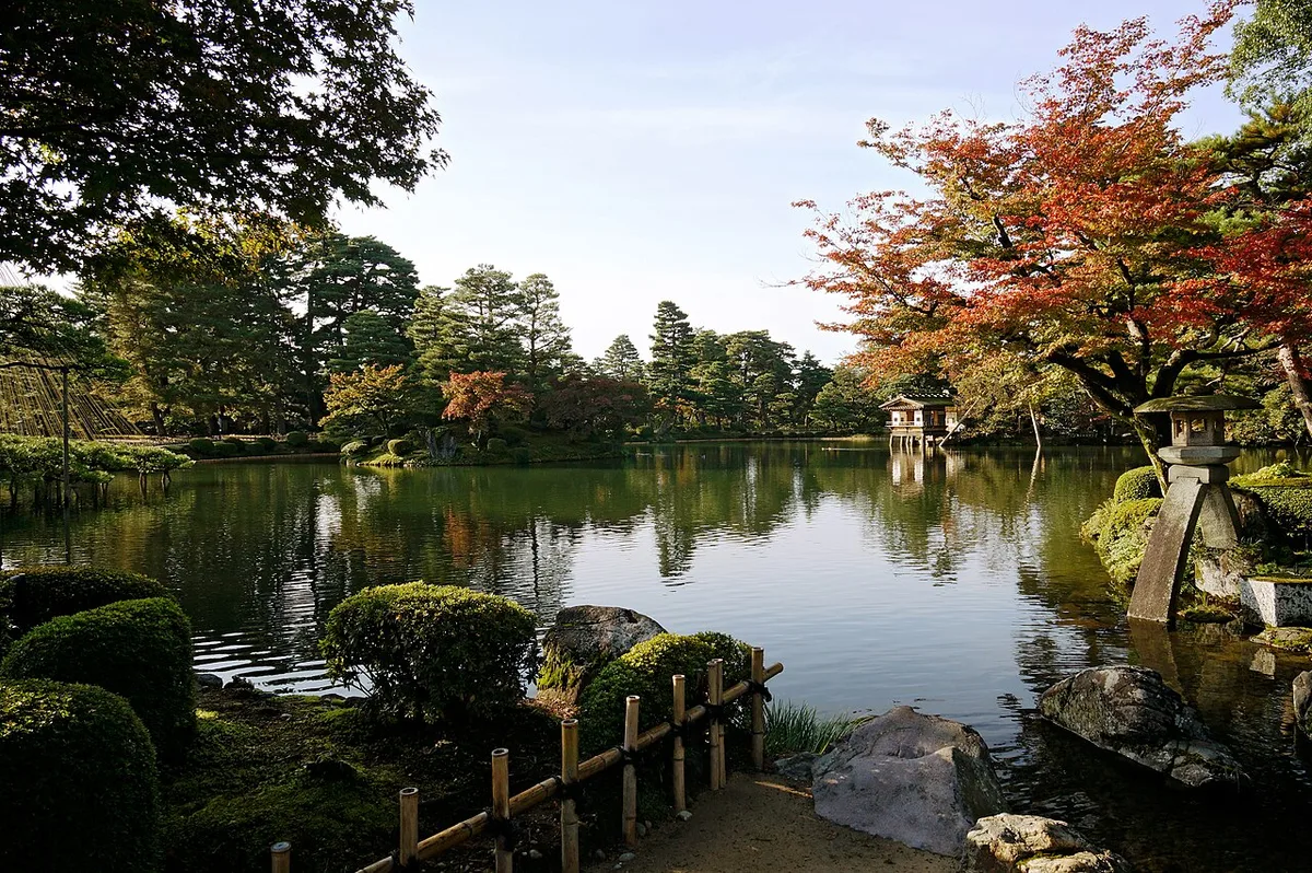 Kasumiga-ike pond at Kenroku-en with the Kotoji stone lantern, pine trees and early autumn maples