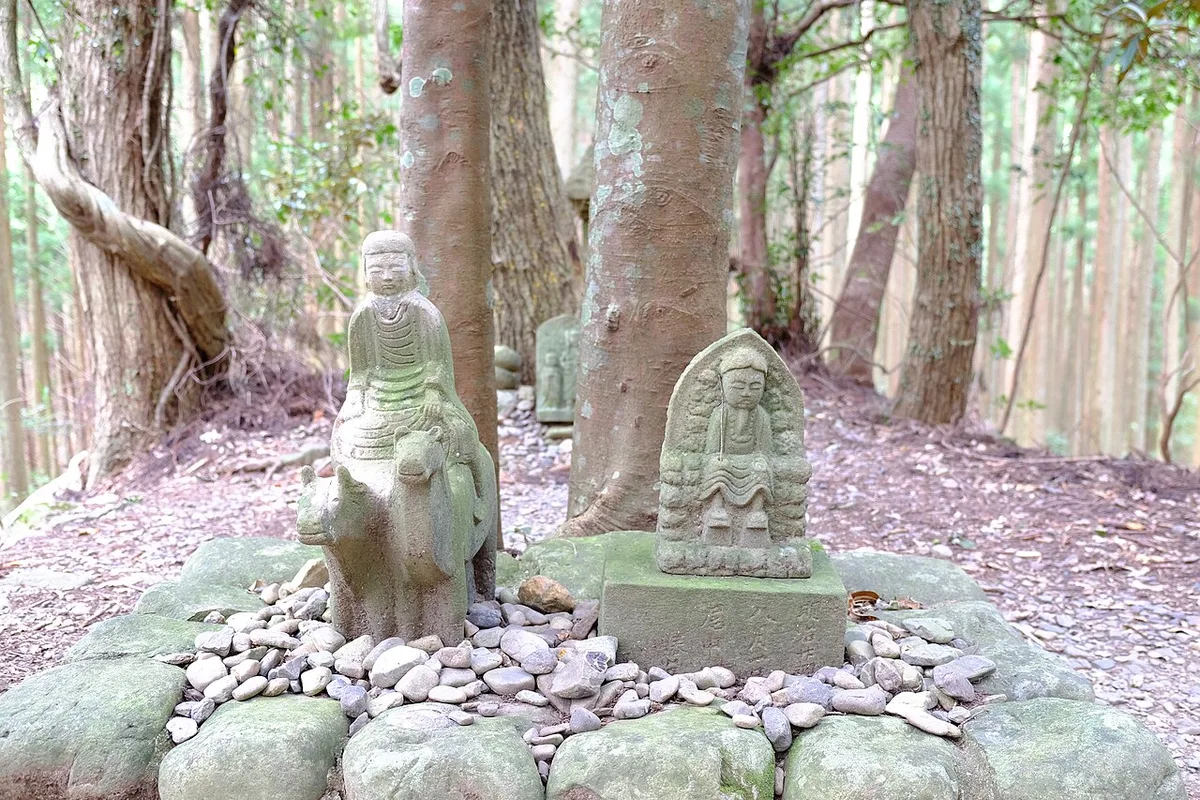 Mossy Gyuba-doji stone statues among cedar trees beside the Kumano Kodo trail