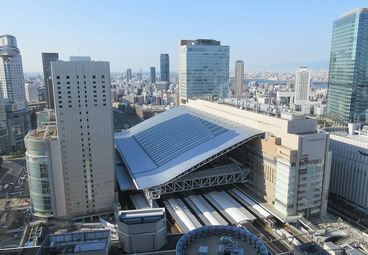 JR Osaka Station's curved roof over the platforms, seen from above among Umeda high-rises
