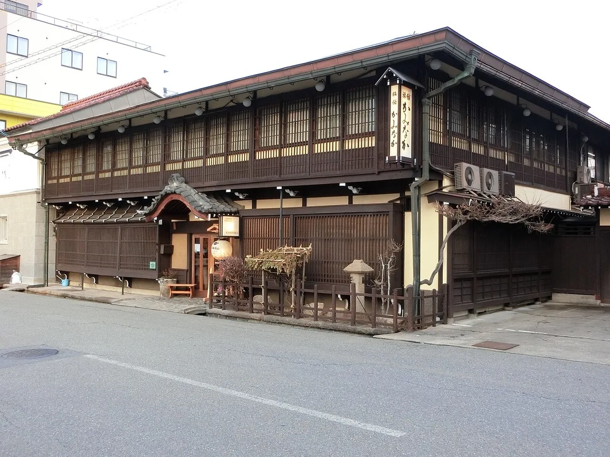Two-storey wooden exterior of a traditional ryokan in Takayama with lattice windows and lanterns