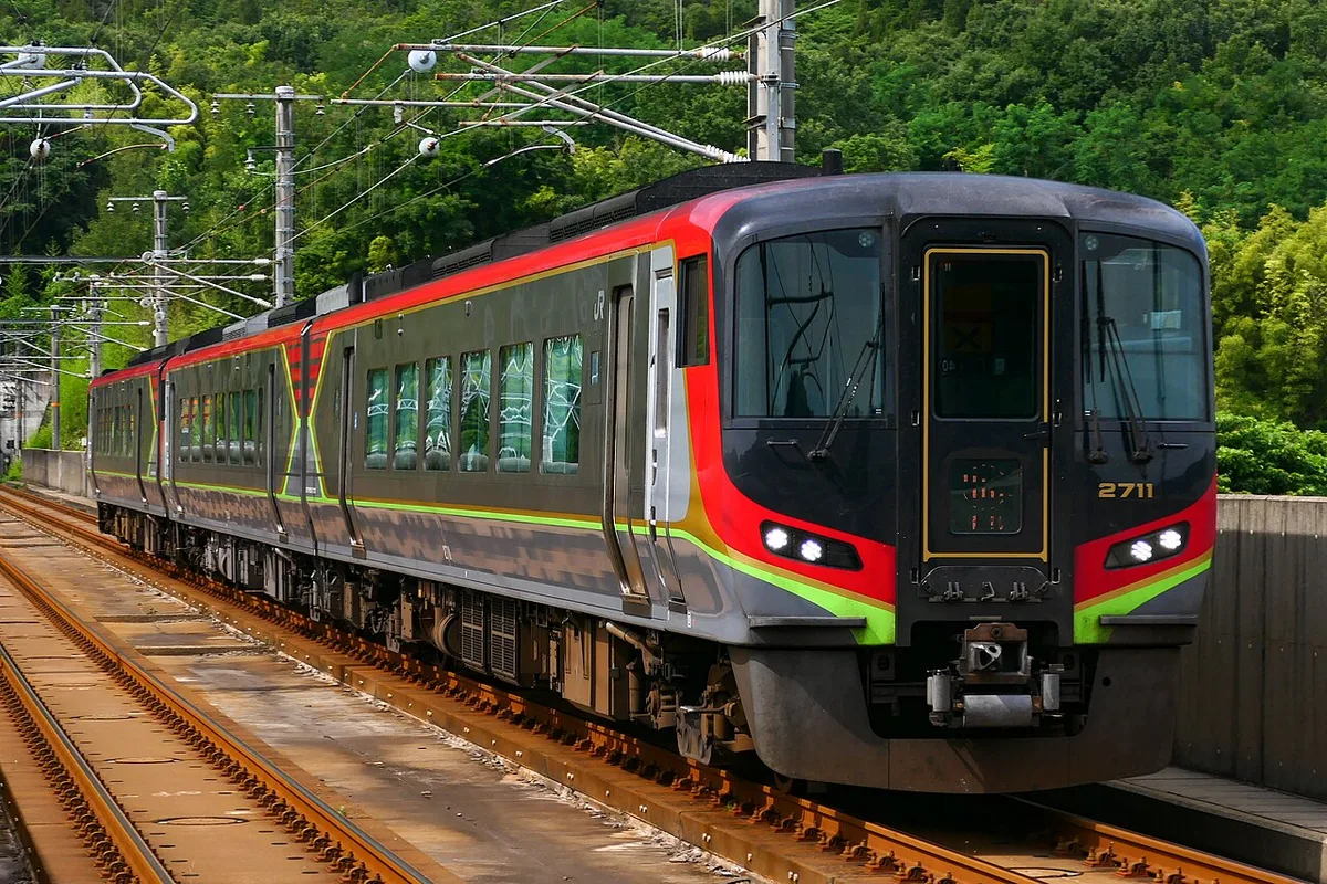 Red, black and green JR Shikoku Series 2700 diesel limited express train on a curve