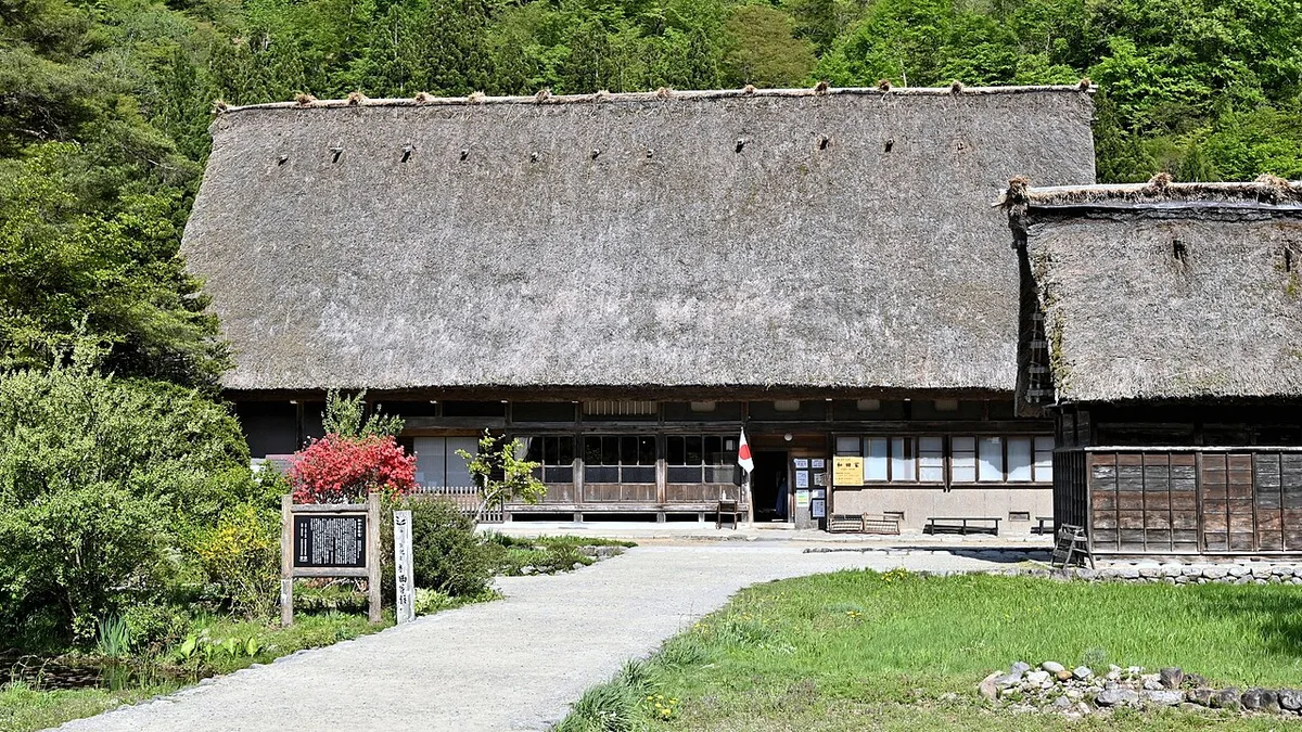 Large thatched gassho-style farmhouse of the Wada family behind a lawn and path in Shirakawa-go