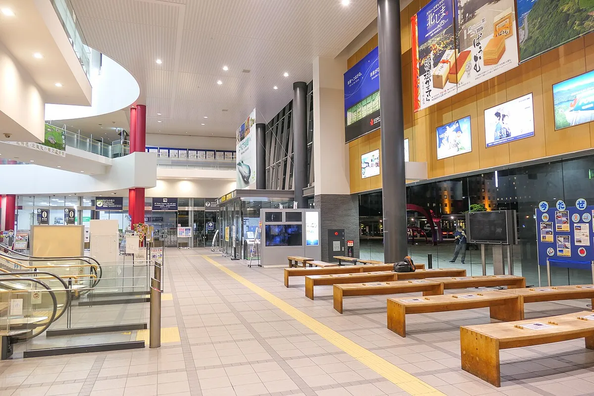 The bright concourse inside JR Hakodate Station with escalators, benches and shop fronts