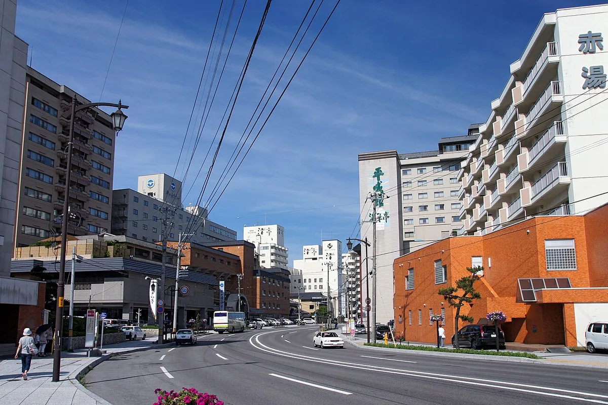 A wide street in Yunokawa Onsen lined with multi-storey hotel buildings under a blue sky