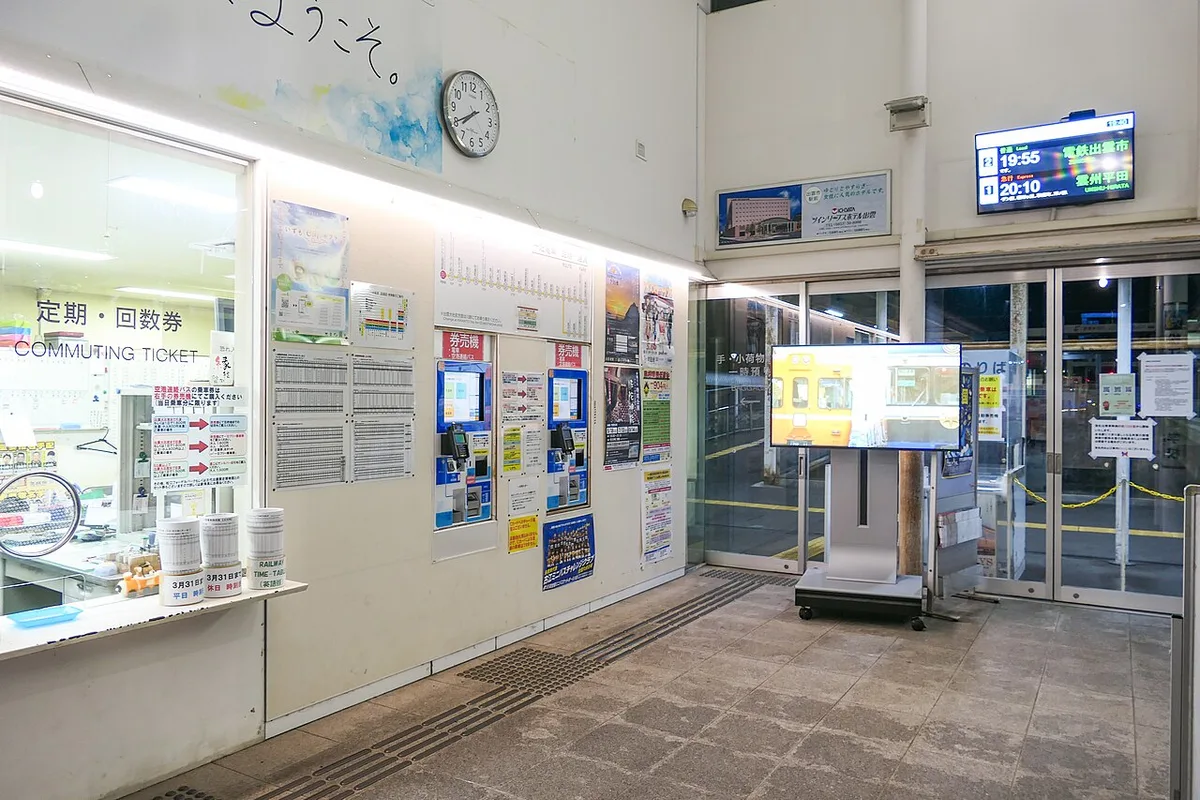 Ticket window, fare machines and departure board inside the gate area of Matsue Shinjiko-Onsen Station at night