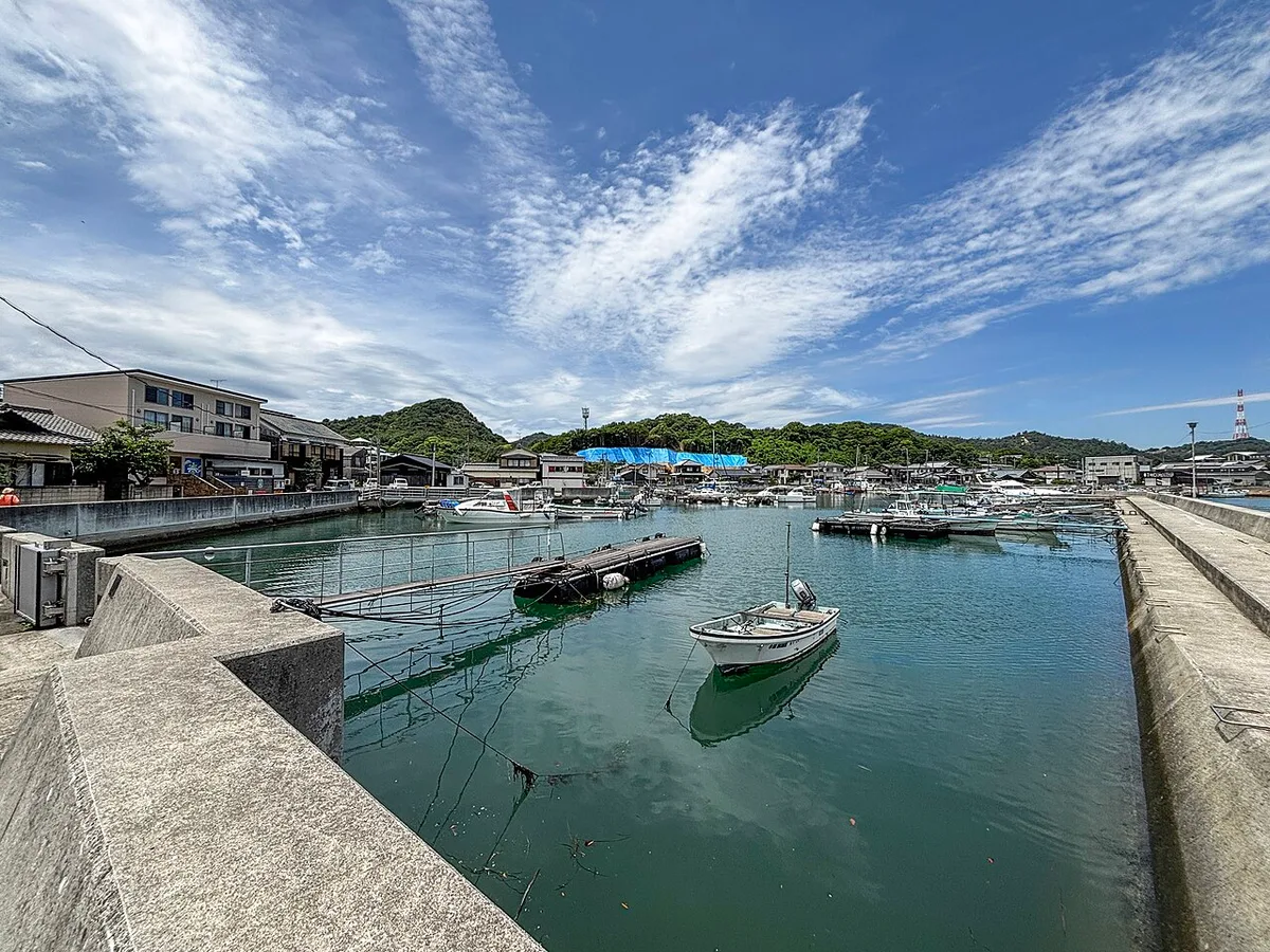 Small harbour at Honmura on Naoshima with boats moored between concrete piers under a blue sky